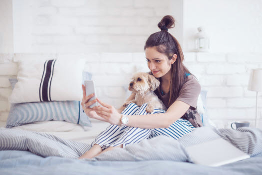 Femme qui se prend en photo avec son chien sur son lit